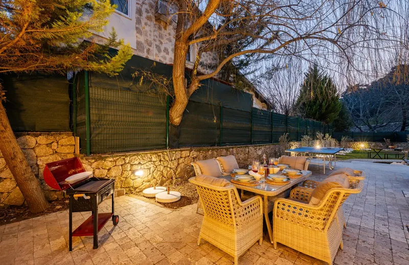 Backyard patio with a dinner table and grill at dusk