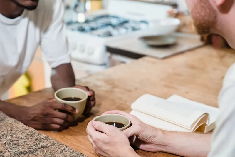Two men talking over coffee at a kitchen counter