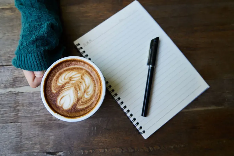 Notebook and a cup of coffee on a wooden table